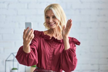 Şık giyinmiş zarif bir kadın cep telefonuyla selfie çekiyor..