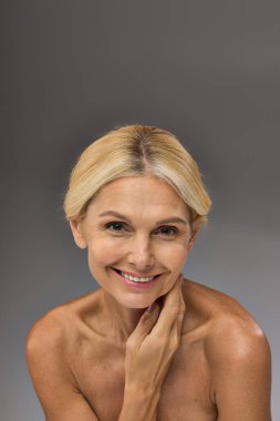 Hoş, olgun bir kadın zarif bir şekilde poz verir ve kameraya gülümser..