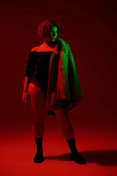 stock image A woman in a coat standing before a striking red backdrop.