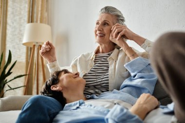 Two women share a loving moment seated on a couch together. clipart