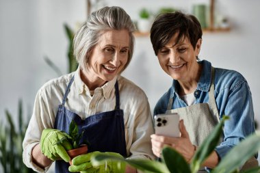 Two women in aprons engrossed in their phones. clipart
