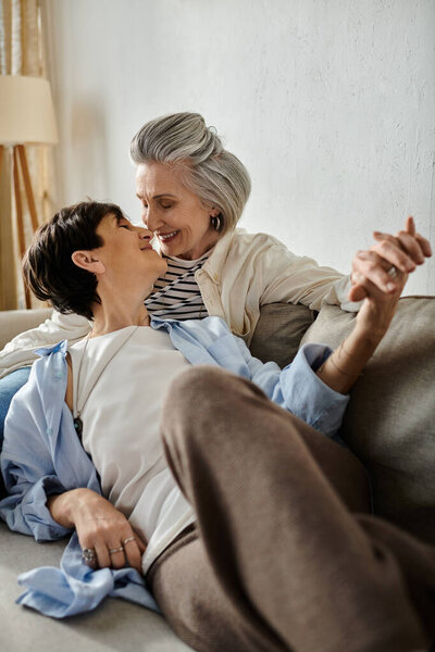Affectionate moment between two senior women hugging on a couch.