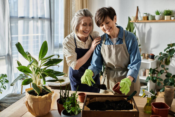 Two women in aprons plant a sprout in a pot in a cozy setting.