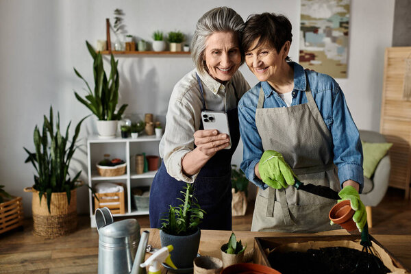 Две женщины в саду фотографируют свои растения.