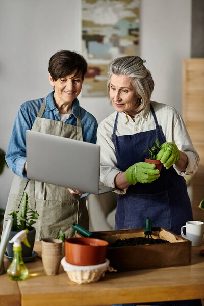 Две женщины, любящая взрослая лесбийская пара, поглощенная ноутбуком в пышном саду.