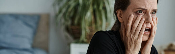 A middle-aged woman covering her face with her hands in despair.