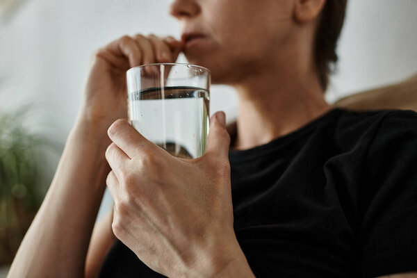 A middle-aged woman peacefully drinking water from a glass.