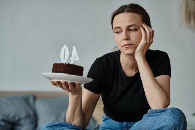 Woman holding a cake with the number 40 on it, celebrating a milestone birthday. clipart