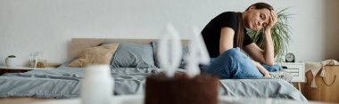 Woman sitting on bed, hands on face