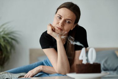 Middle-aged woman sits with cake.