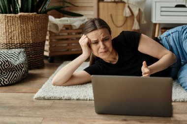 A woman in introspection, lying on the floor fixated on her laptop screen.