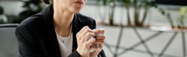 A middle-aged woman sits at a table, experiencing a moment of introspection and contemplation.