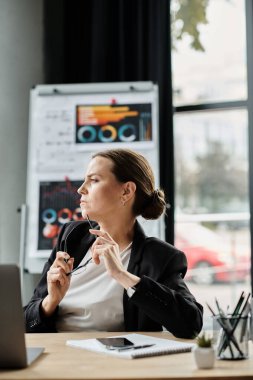 Middle-aged woman stressed, having a mental breakdown while working on laptop at desk.