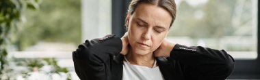 Woman holding neck in pain at office, depression. clipart