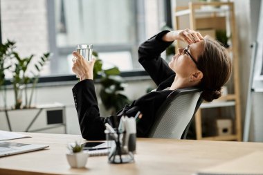 Middle-aged woman sitting at desk with a glass of water.