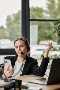 A middle-aged woman wearing a headset is overwhelmed with work at her desk.