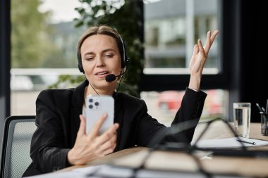 Woman in headset multitasking on phone in office. clipart