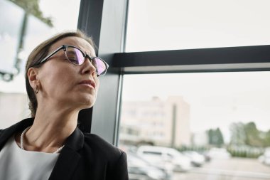 A middle-aged businesswoman in glasses gazes away, depression. clipart