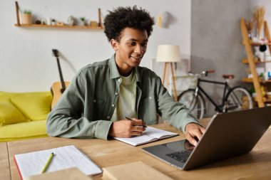 Young man engrossed in online study on laptop at home desk.