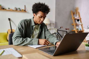 Young African American man focused on studying online at home.