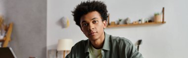 Young man, African American, studying with laptop at home.