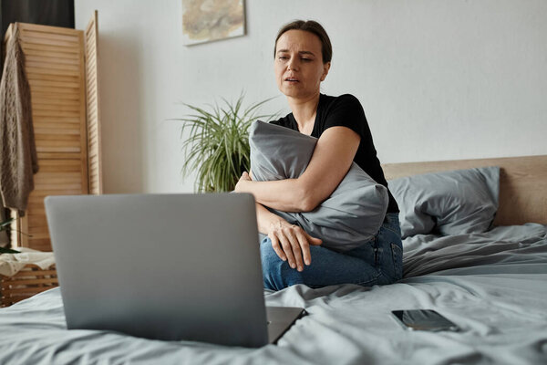 Middle-aged woman finds solace in therapy session on laptop.