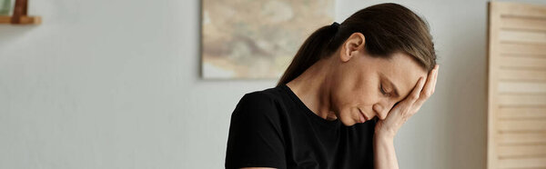 Middle-aged woman with a distressed expression holding her head in her hands.