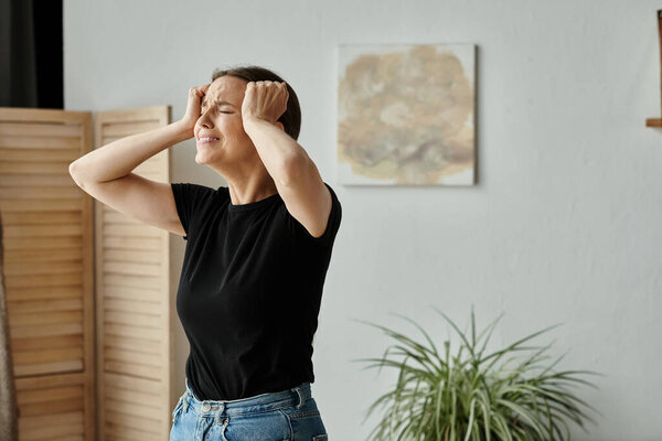 Middle-aged woman expresses distress with hands on head in cozy living room.
