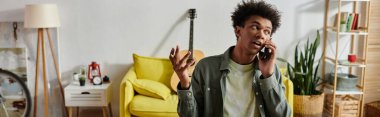 A young African American man converses on phone in cozy living room.
