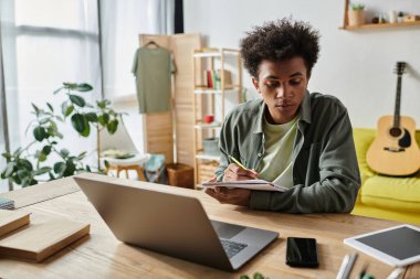 Young man works diligently on laptop in cozy home office.