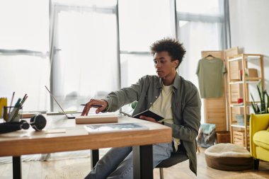 A young man, African American, studies at his home office desk.
