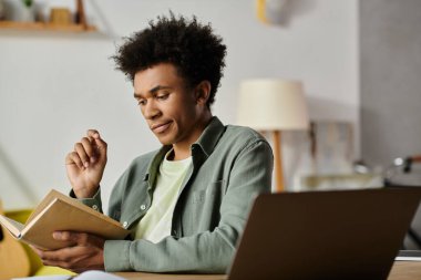 Young man engrossed in book at table.