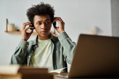 Young man immersing in laptop tunes. clipart