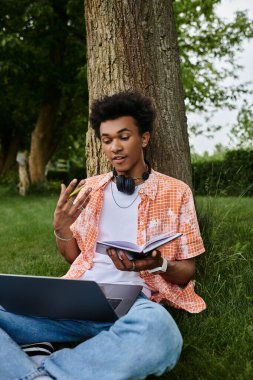 Young man, laptop, headphones, natures embrace.