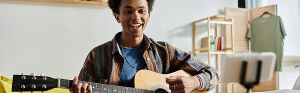 Young man playing acoustic guitar in living room.