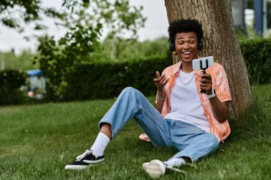 Young man sitting on grass, engrossed with cell phone.