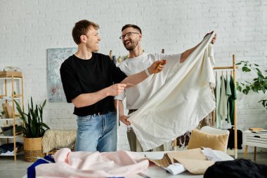 Two men stand side by side in a designer workshop, discussing and crafting trendy attire. clipart