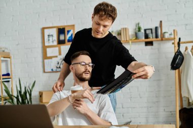 gay couple working on designing trendy attire for his fashion workshop. clipart