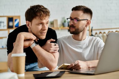 İki adam, bir eşcinsel çift, dizüstü bilgisayarın ekranına doğru eğildiler, moda tasarım işbirliğine daldılar..