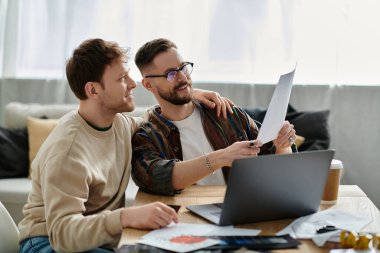 Two men in a designer workshop, working together on a laptop. clipart