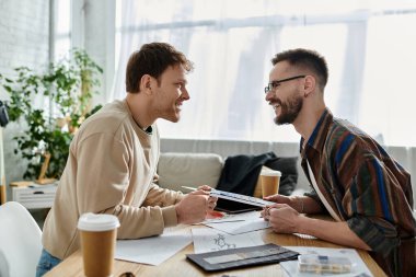 Two creative designers discussing ideas over a table in a trendy workshop. clipart