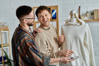 İki adam bir tasarımcı atölyesinde bir mankenin yanında çalışıyor, eşsiz giysiler tasarlıyorlar..