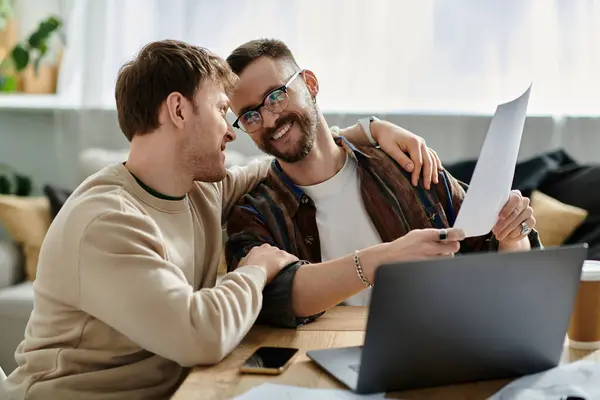 stock image Two men in a designer workshop work together on a laptop, focused and attentive.