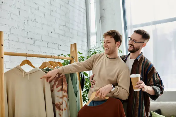 stock image Two men, a gay couple, stand together in a designer workshop, collaborating on trendy attire.
