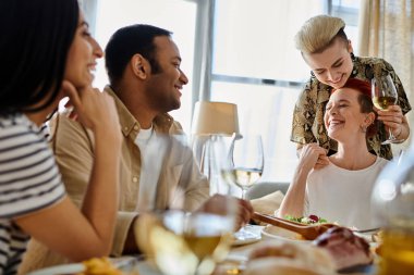 Sevgi dolu lezbiyen bir çiftin de aralarında bulunduğu bir grup insan, birlikte yemek yiyorlar..