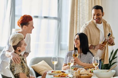 Çeşitli gruplar bir masada yemek ve içeceklerin keyfini çıkarıyor..