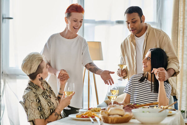A diverse group of people enjoy a meal together at a table filled with food.