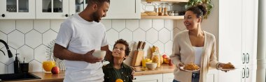 A man and a woman, a loving African American family with son, standing together in a kitchen. clipart