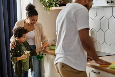 Afro-Amerikan ailesi mutfakta genç bir çocukla temizlik yapıyor..