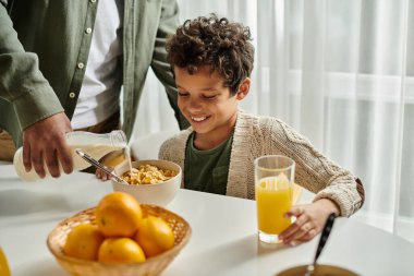 Genç bir çocuk masada oturmuş, bir kase mısır gevreği yiyor..